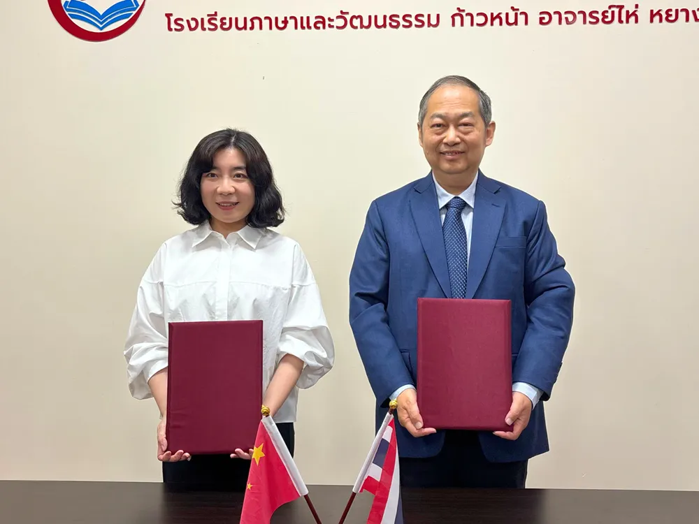 ผู้แทนจาก Jinbu และ Shenyang City University ถือเอกสารลงนามความร่วมมือ พร้อมธงไทย–จีน–อังกฤษ