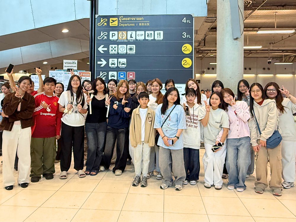 นักเรียน Jinbu ถ่ายภาพหมู่หน้าป้ายบอกทางสนามบินประเทศไทย