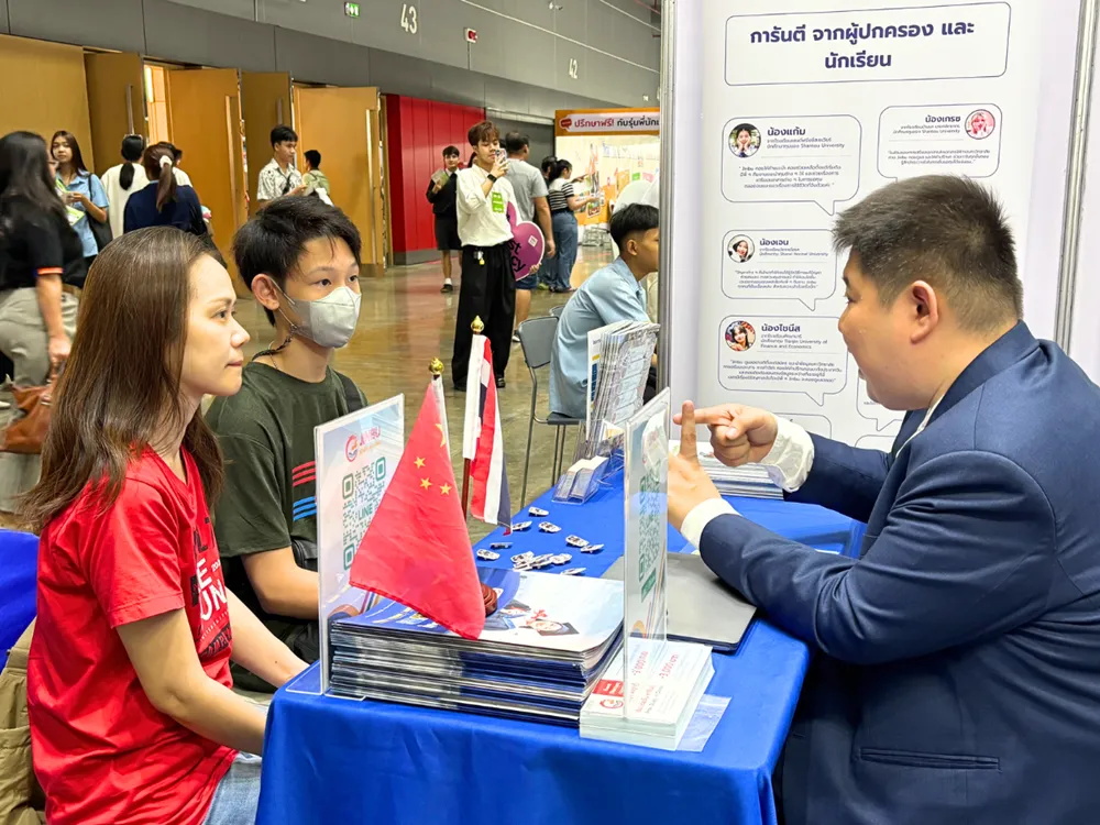บูธให้คำปรึกษา Jinbu ในงานนิทรรศการการศึกษา มีผู้แทนพูดคุยกับผู้ปกครองและนักเรียน พร้อมธงจีน–ไทย