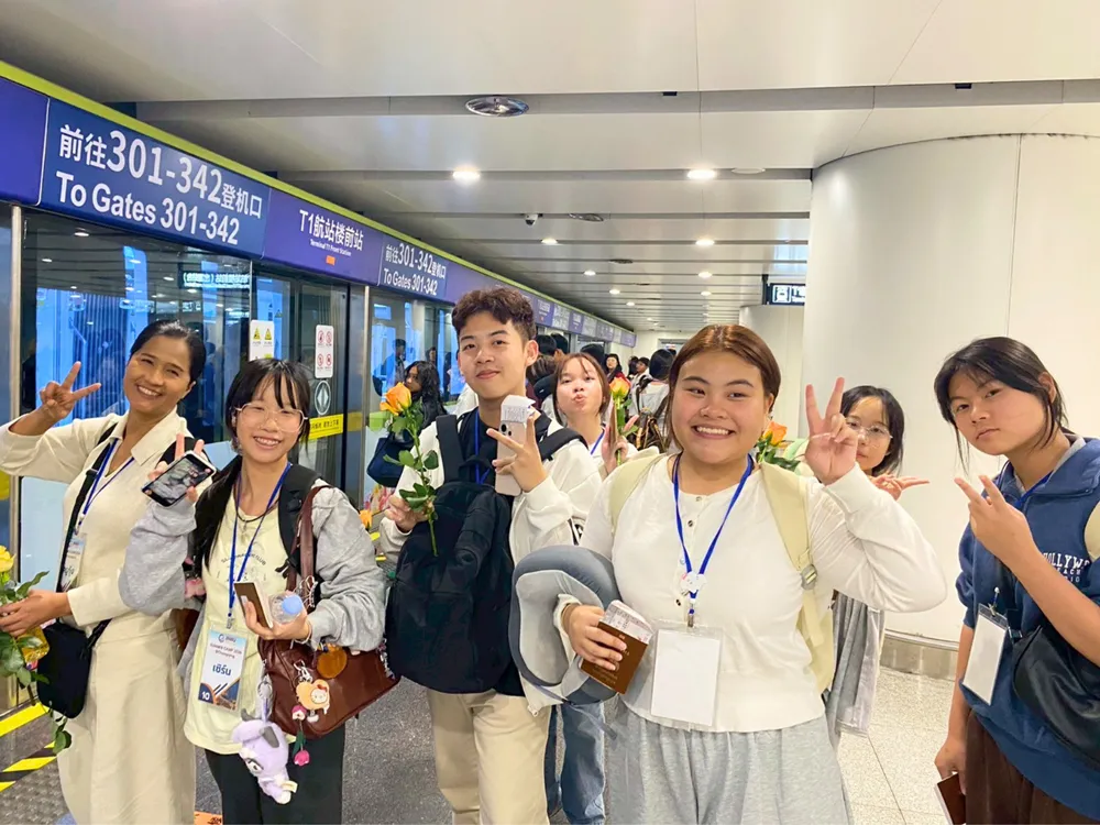 นักเรียน Jinbu ถ่ายภาพหมู่ที่สนามบินจีน ใกล้ป้ายทางออกขึ้นเครื่อง