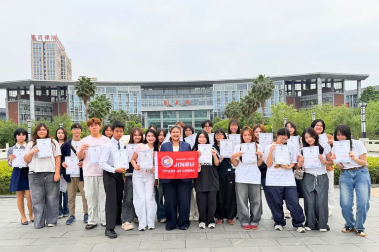 นักเรียนไทยถ่ายภาพหมู่หน้ามหาวิทยาลัยในจีน ถือประกาศนียบัตรและแบนเนอร์ Jinbu Study in China รอบมีนาคม–เมษายน 2569