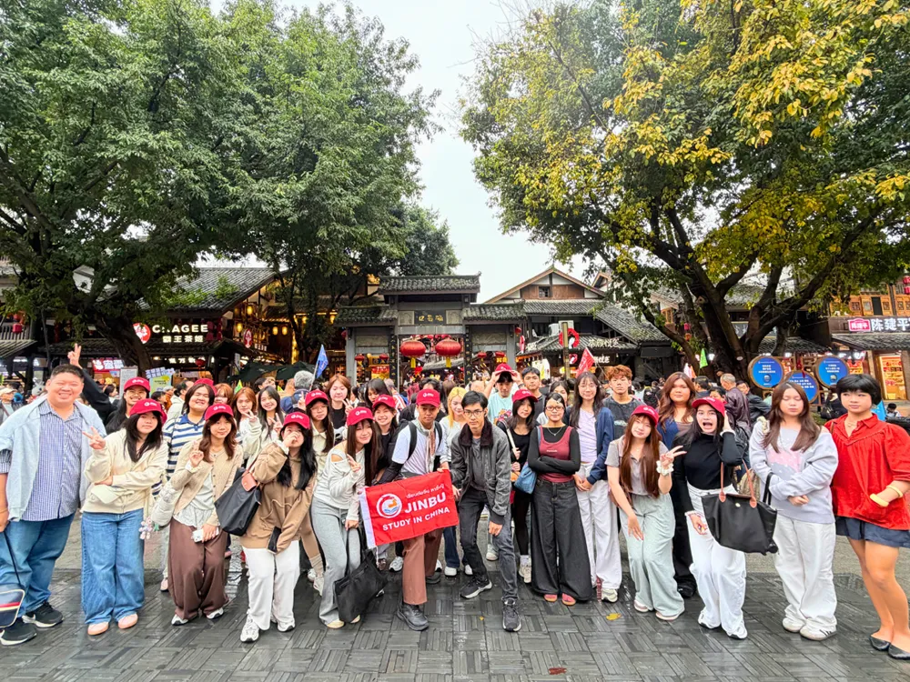 นักเรียนไทยสวมหมวกสีแดง ถ่ายภาพหมู่พร้อมแบนเนอร์ Jinbu Study in China ในย่านวัฒนธรรมจีน รอบมีนาคม–เมษายน 2569