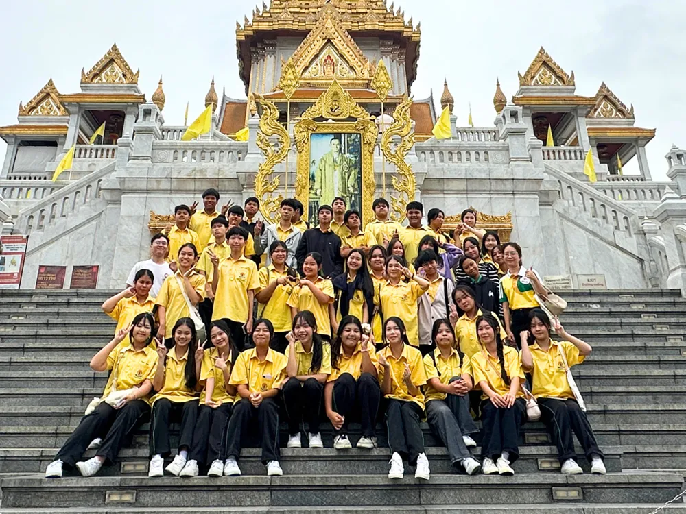 นักเรียนสวมเสื้อเหลืองถ่ายภาพหมู่หน้าวัดไทยโบราณระหว่างกิจกรรม China Day Camp