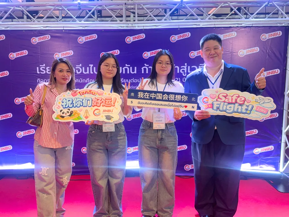 นักศึกษาถ่ายภาพกับป้ายกิจกรรมปฐมนิเทศ Jinbu พร้อมข้อความอวยพรหลายภาษา