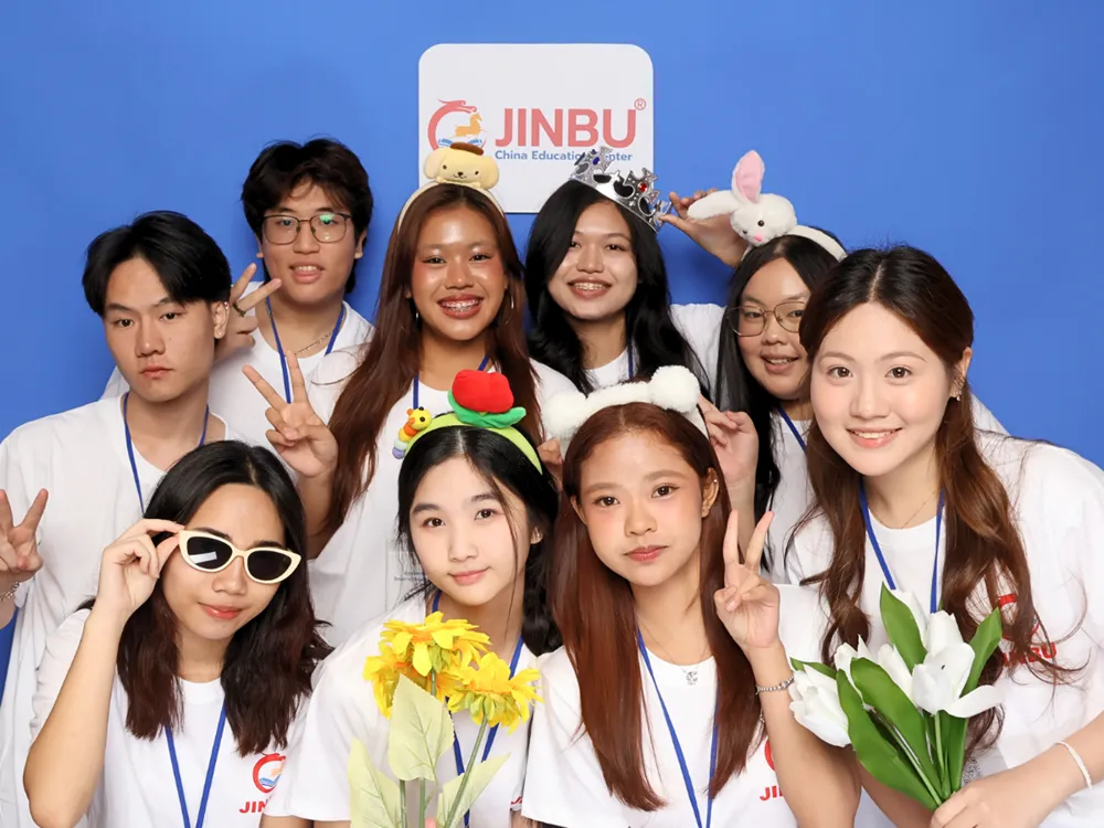 นักศึกษากลุ่มเล็กถ่ายภาพหมู่กับดอกไม้และป้าย Jinbu China Education Center