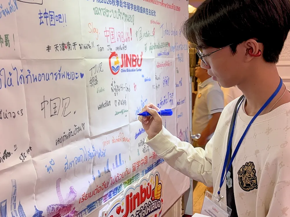 นักศึกษาเขียนข้อความให้กำลังใจบนแบนเนอร์กิจกรรมปฐมนิเทศ Jinbu