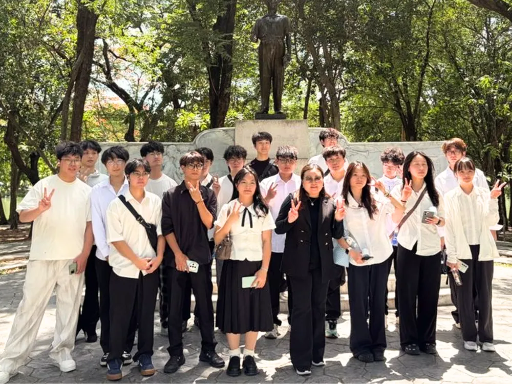 นักศึกษาจีนถ่ายภาพหมู่หน้ารูปปั้นในสวนสาธารณะประเทศไทย