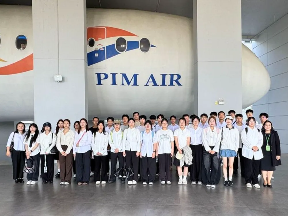 นักศึกษาจีนถ่ายภาพหมู่หน้าจำลองเครื่องบิน PIM AIR ในโครงการแลกเปลี่ยน