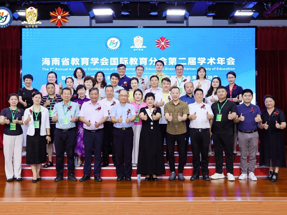ผู้เข้าร่วมประชุมวิชาการ Hainan Society of Education ถ่ายภาพหมู่หน้าป้ายงาน