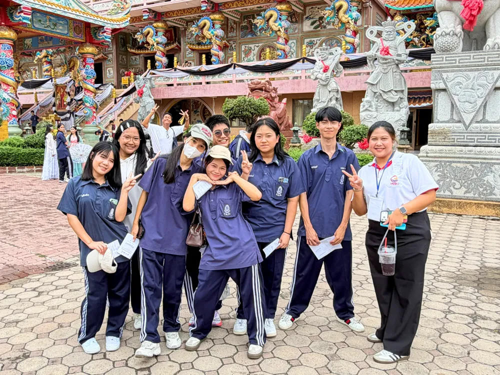 นักเรียนกลุ่มเล็กสวมชุดนักเรียนสีน้ำเงิน ถ่ายภาพหน้าศาลเจ้าจีนในกิจกรรมค่ายภาษาและวัฒนธรรมจีน