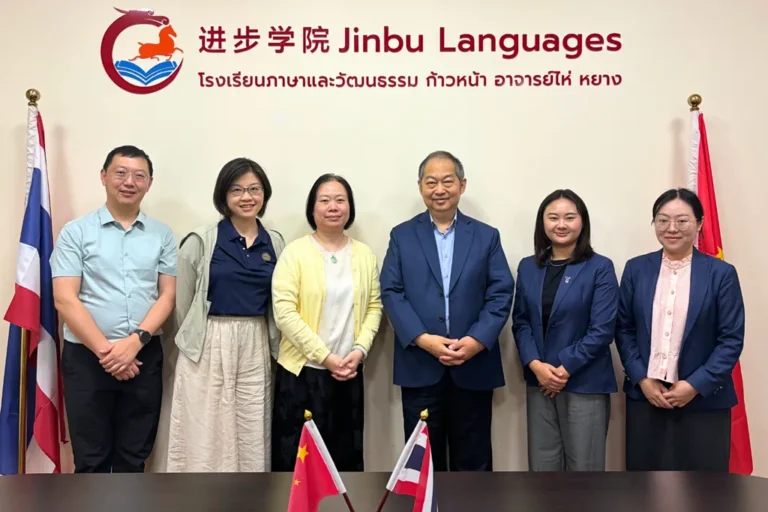 ผู้บริหารมหาวิทยาลัยซูโจวและ Jinbu ยืนถ่ายภาพหน้าป้าย Jinbu Languages พร้อมธงชาติไทยและจีน