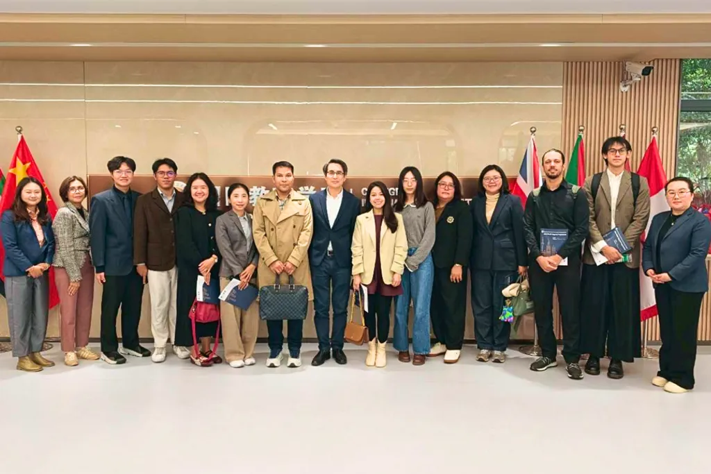 คณะอาจารย์ไทยถ่ายภาพหมู่หน้าป้าย School of International Education พร้อมธงนานาชาติ