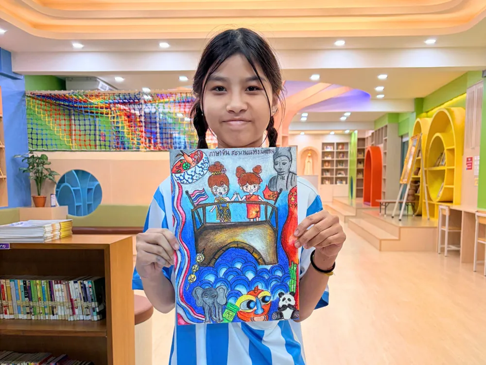 นักเรียนถือภาพวาดประกวดหัวข้อภาษาจีนสะพานแห่งมิตรภาพ