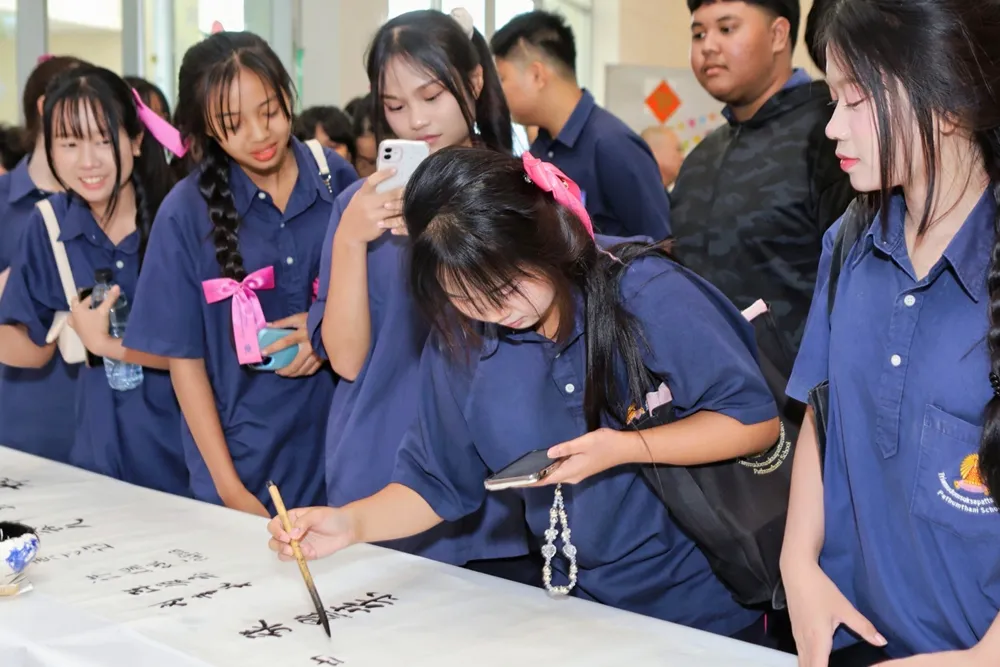 นักเรียนสวมชุดนักเรียนไทยร่วมกิจกรรมเขียนพู่กันจีนในงานเทศกาลศิลปะอักษรจีน