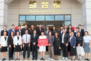 ผู้บริหารและคณะอาจารย์ไทยถ่ายภาพหมู่หน้าอาคารอเนกประสงค์ของ Hainan Maple Leaf International School ในโครงการศึกษาดูงานการศึกษาไทย–จีน